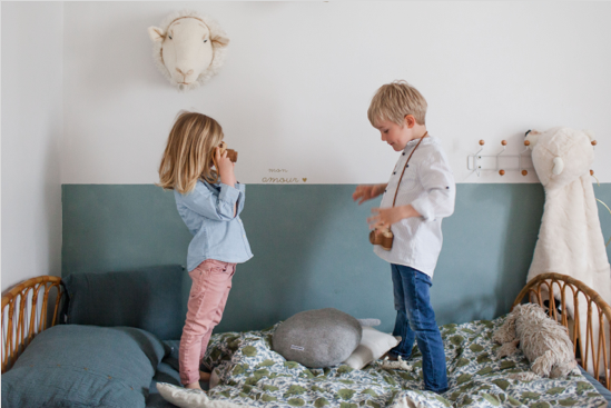 2 enfants debout sur un lit