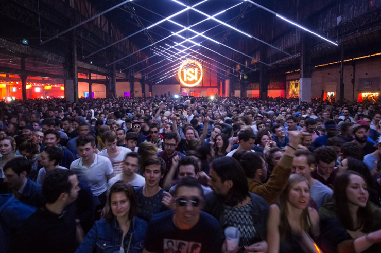 Photo de la foule prise lors d'un concert dans un hangar avec des jeux de lumières